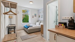 A modern bedroom with a bed, bedside table, and a window with a view of trees. - Vorstadtoase für 2 - 2023 eröffnet - Netflix, Parken, Queensize-Bett, Nähe BER (Eichwalde)