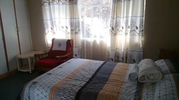 A hotel room with a bed, a red chair, and a small table. - Neat guest suite with office corner - 2101 (Harare)