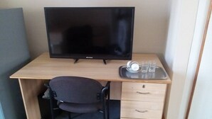 A wooden desk with a black chair, a television, and a tray with cups and glasses. - Neat guest suite with office corner - 2101 (Harare)