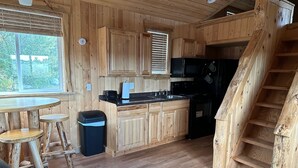 Un intérieur rustique en bois comprenant une cuisine, un coin repas et un escalier.