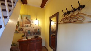 Un couloir avec une armoire en bois, un miroir et un porte-manteau fixé au mur.