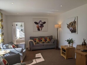 A living room with a sofa, a coffee table, a lamp, and artwork on the walls.