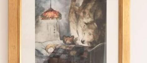 Ein gerahmtes Kunstwerk, das einen Bären und einen Hund auf einem Tisch zeigt, über dem eine Pendelleuchte hängt.