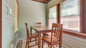 A dining area with a wooden table and chairs, light green walls, and a window with blinds. - Sunny + Spacious Dayton Condo ~ 1 Mi to Downtown! (Dayton)