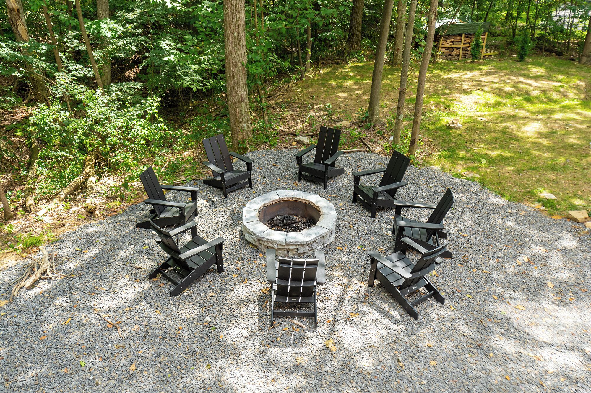 A circular seating arrangement around a stone fire pit in a forested area.