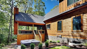 A modern log cabin with a covered outdoor seating area, a stone fireplace, and a well-maintained garden. - Black Diamond Lodge by Taylor Made Deep Creek (McHenry)