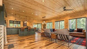 A spacious wooden cabin interior with a kitchen, dining area, and seating space. - Black Diamond Lodge by Taylor Made Deep Creek (McHenry)