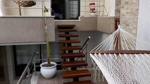 Un espacio exterior moderno con escaleras de madera, una hamaca y una planta en maceta.