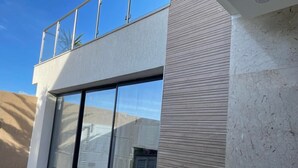Un edificio moderno con entrada de vidrio, un balcón y una planta en maceta.