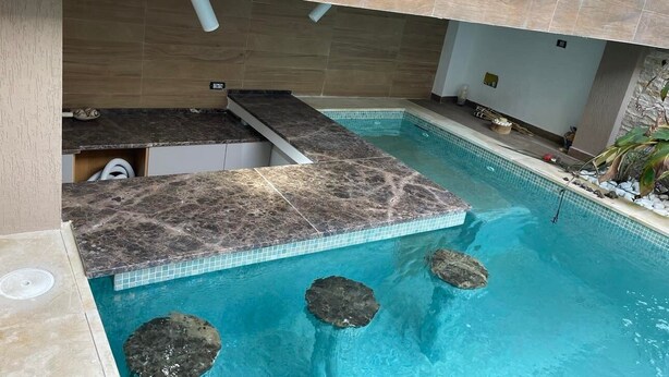 Una piscina con un suelo de piedra y una pequeña cascada.