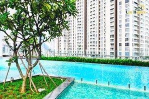 A swimming pool with a tree in the foreground and high-rise buildings in the background.