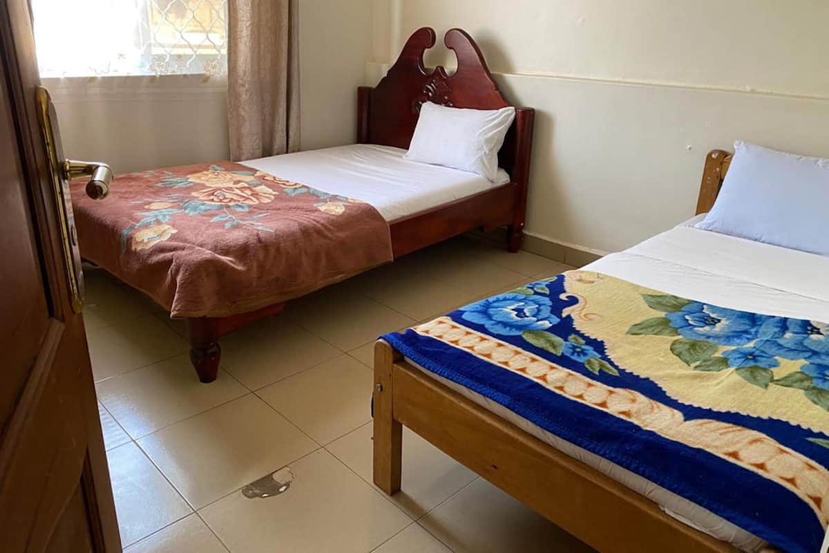 A room with two wooden beds, each with a distinct floral bedspread.