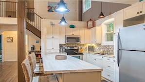 A kitchen with white cabinets, a central island, a microwave, and a refrigerator. - Muskoka Serenity - Four Bedroom Cottage, Sleeps 8 (Torrance)