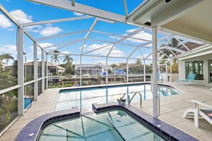 A covered outdoor swimming pool with a clear view of the surrounding neighborhood, including houses and palm trees.