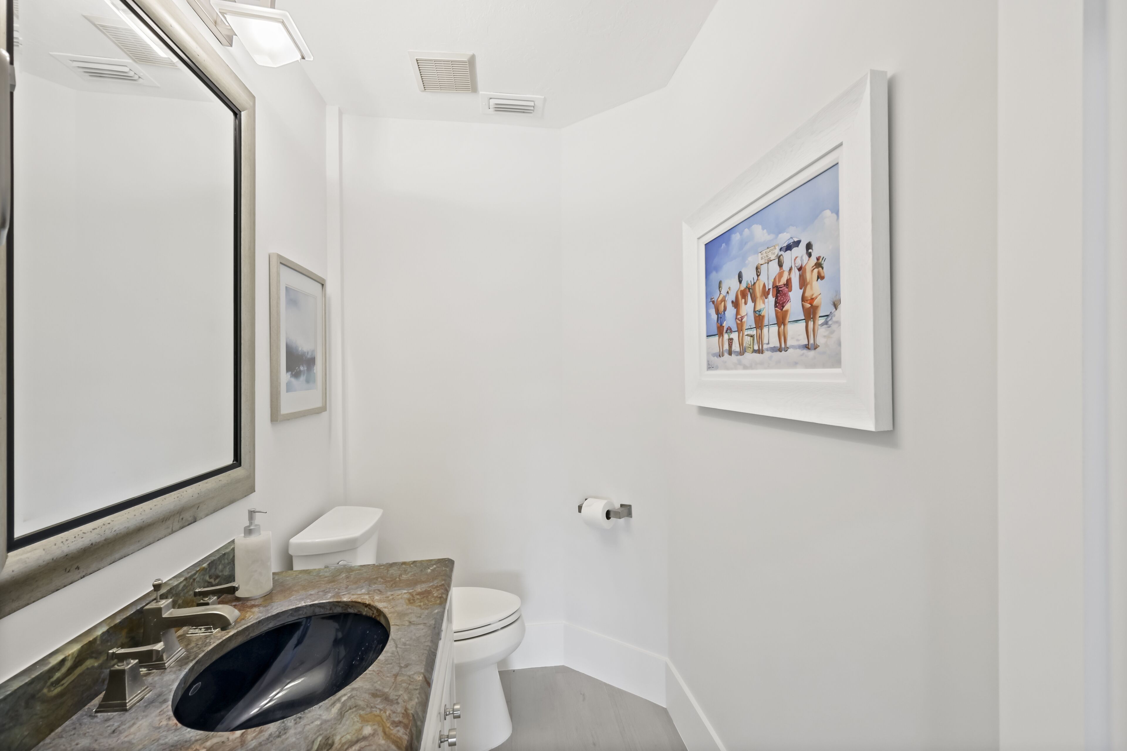 Een badkamer met een marmeren wastafel, toilet en een gekaderd schilderij aan de muur.