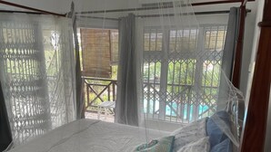 Een slaapkamer met een bed, een raam met uitzicht op de omgeving en een balkon met een tafel en stoelen.