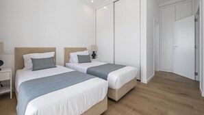 A modern bedroom with two beds, a wardrobe, and a nightstand. - Casas da Luz - Casa da Latada by Homie (Ponta do Sol)