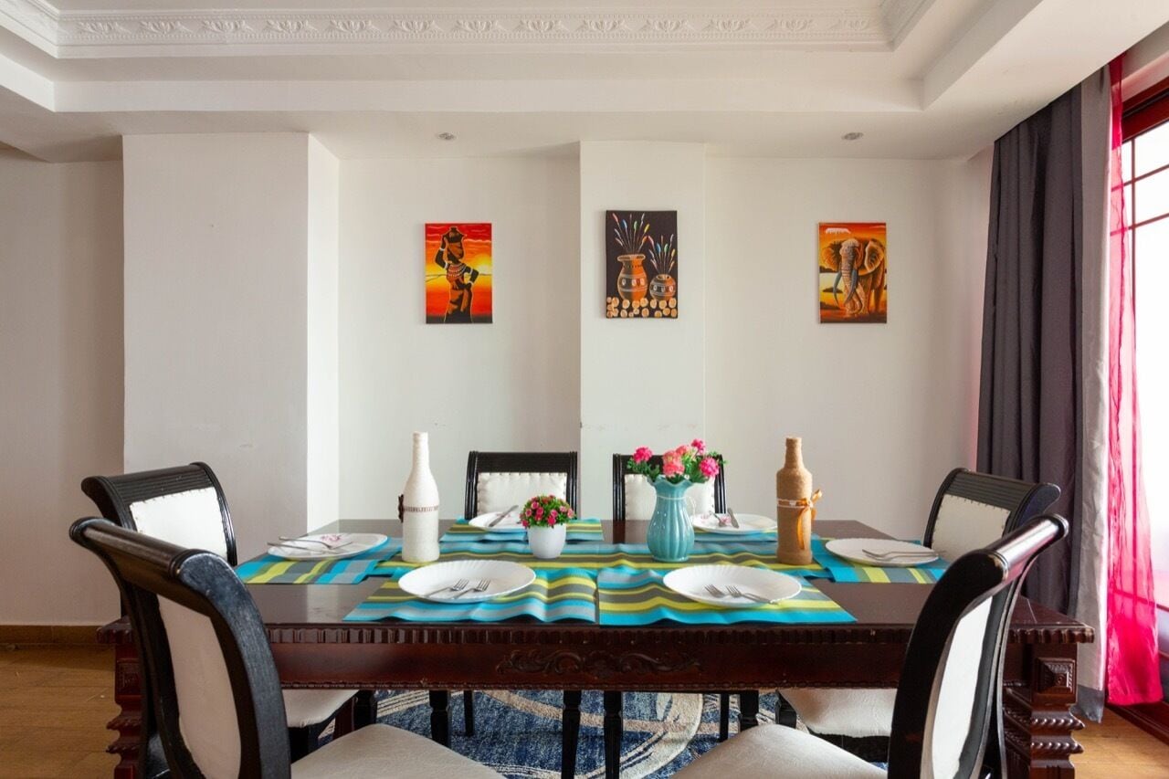 A dining area with a wooden table, four chairs, and artwork on the walls.