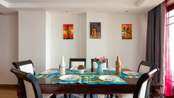 A dining area with a wooden table, four chairs, and artwork on the walls.