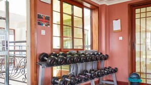 A gym with a rack of dumbbells and barbells, a bulletin board, and a view through large windows. - Skyline Apartment 3 Bedroom with SQ-801 (Nairobi)