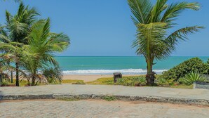 Un camino pavimentado que lleva a una playa con palmeras y vista al océano.