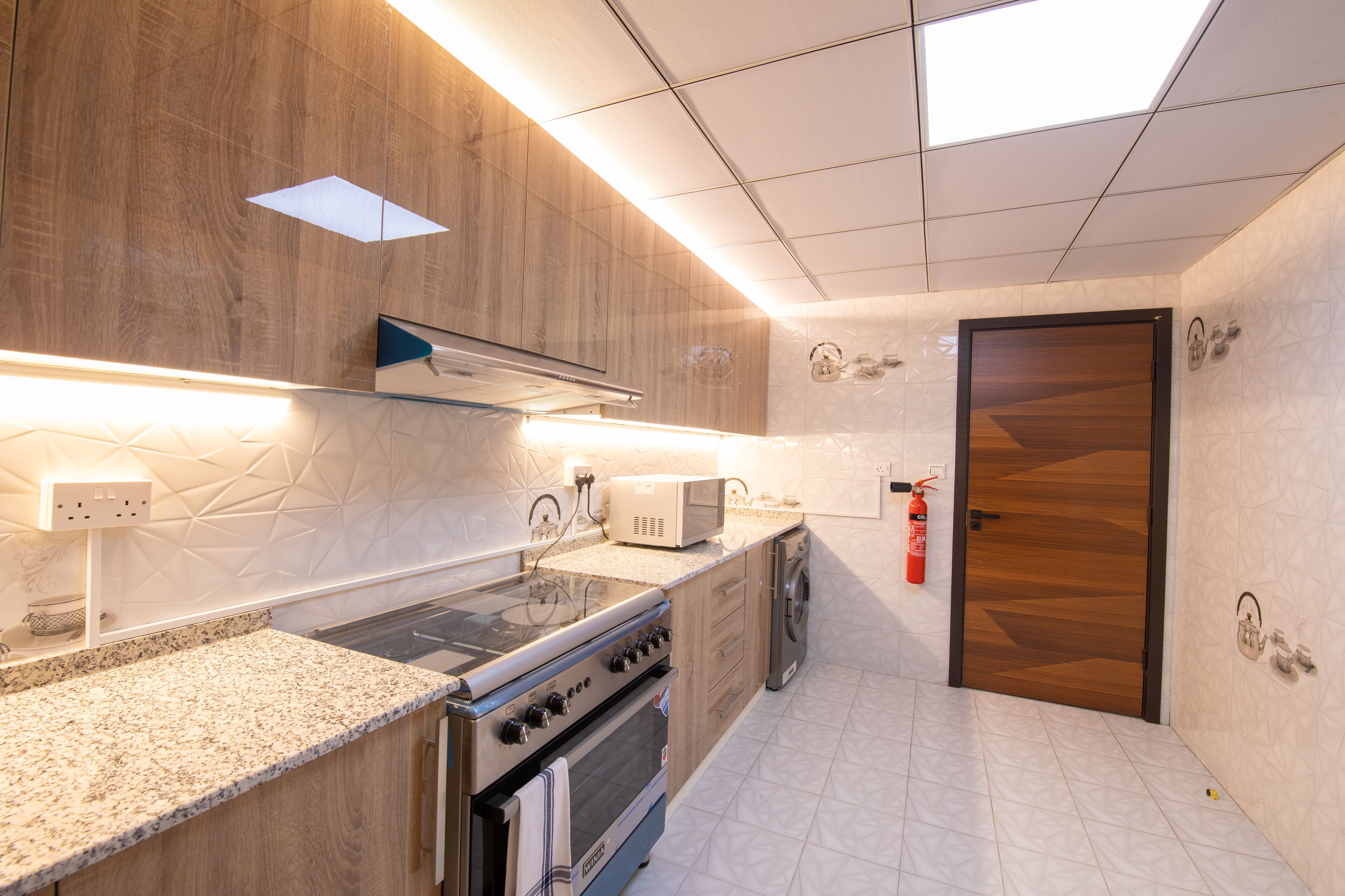 A modern kitchen with a built-in oven, microwave, and stainless steel range.