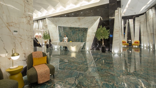 Eine moderne Lobby mit Marmorböden, einem Empfangstresen und Sitzbereichen.