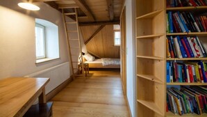 Una habitación con una cama en literas, un escritorio de madera, una estantería y una escalera.