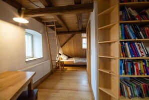 Ein Zimmer mit Hochbett, Holzschreibtisch, Bücherregal und einer Leiter.