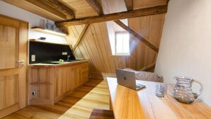 Un interior de madera con una zona de cocina, una computadora portátil sobre una mesa y una jarrón.