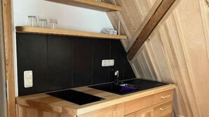 Una cocina compacta con armarios de madera, una encimera negra y un lavamanos pequeño.