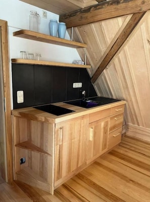 Eine kompakte Küche mit Holzschränken, einer schwarzen Arbeitsplatte und einem kleinen Spülbecken.