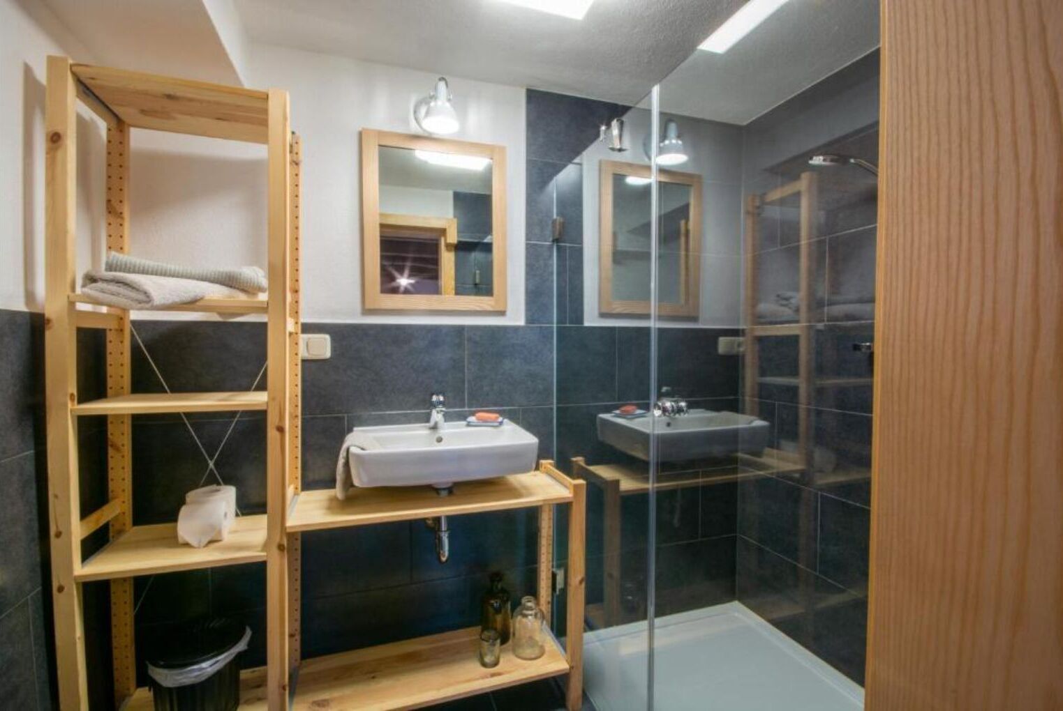 Une salle de bain moderne avec un meuble-lavabo en bois, deux vasques, une douche en verre et un miroir au-dessus du meuble-lavabo.