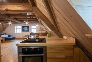 Eine moderne Küche mit Holzbalken, einem eingebauten Herd und einem Essbereich mit einem blauen Sofa.