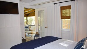 A bedroom with a bed, a door leading to an outdoor area, and a window with curtains.