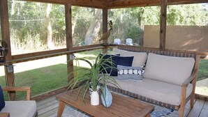 A wooden deck with a sofa, a table, and a potted plant.