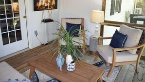 A cozy room with a wooden table, chairs, a potted plant, and a television displaying a fireplace.