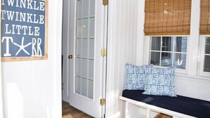 A room with a white door, a bench with patterned cushions, and a sign with the text "TWINKLE TWINKLE LITTLE STAR".