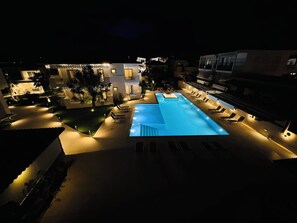 Una piscina al aire libre, sillones reclinables de piscina