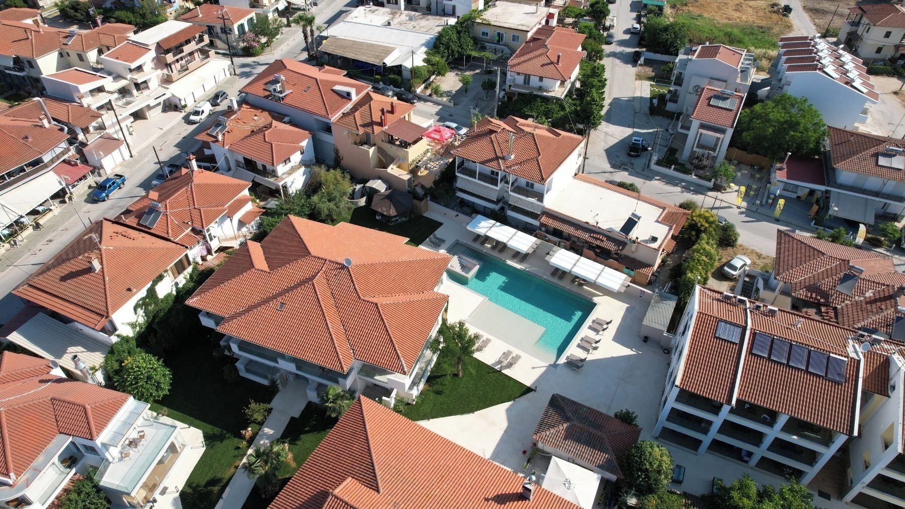 An aerial view of a residential area with multiple houses, a swimming pool, and a small parking area.