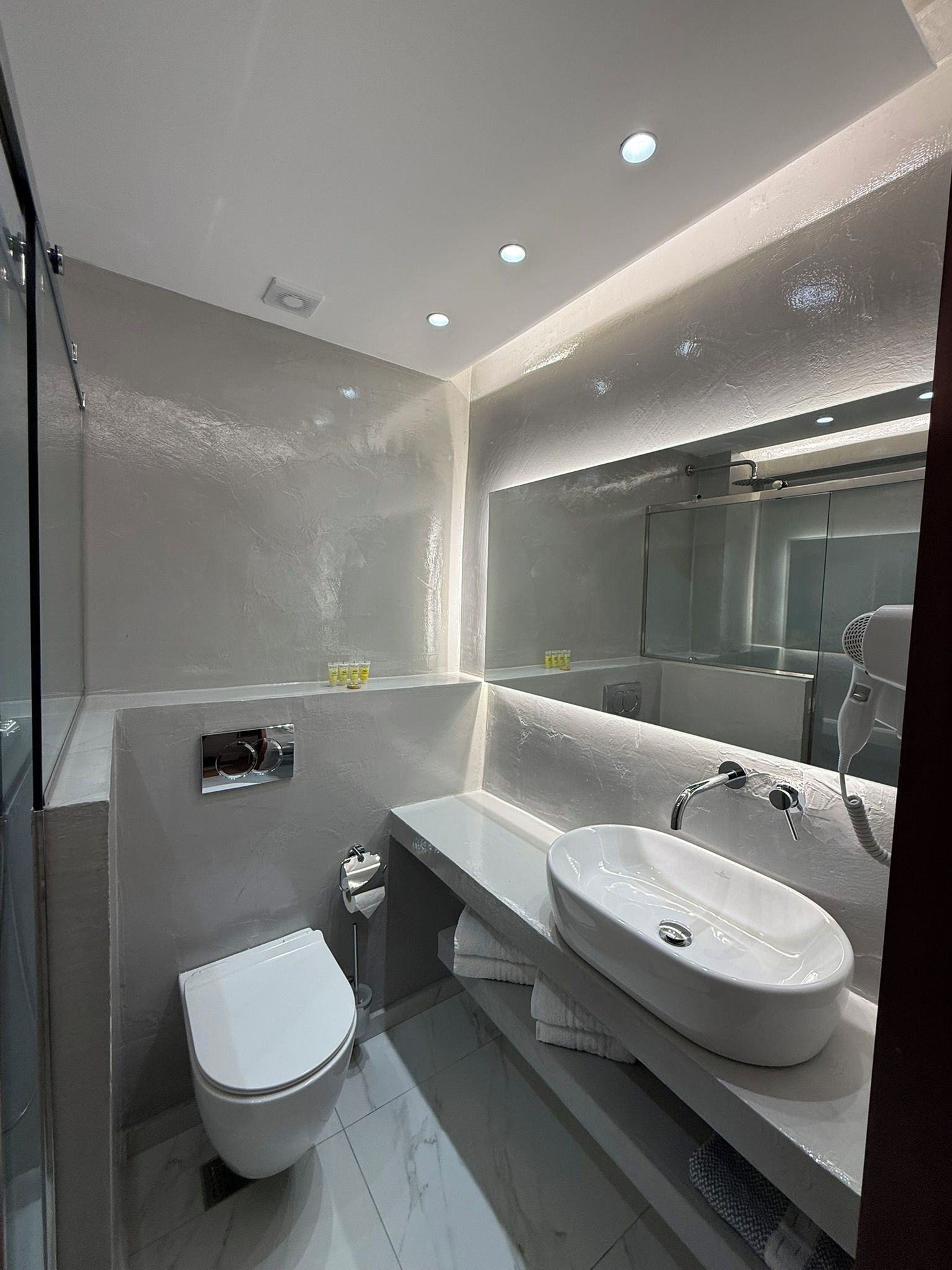 A modern bathroom with a toilet, sink, and shower.