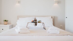 A neatly made bed with white linens, a tray with breakfast items, and a small potted plant on a bedside table. - Locanda villas Lefkada B (Lefkada)