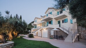 A multi-story building with a stone facade, a covered outdoor seating area, and a staircase leading to the upper floors. - Locanda villas Lefkada B (Lefkada)