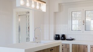A modern kitchen with a central island, white cabinetry, and a built-in wine cooler. - Locanda Villa Lefkada C (Lefkada)