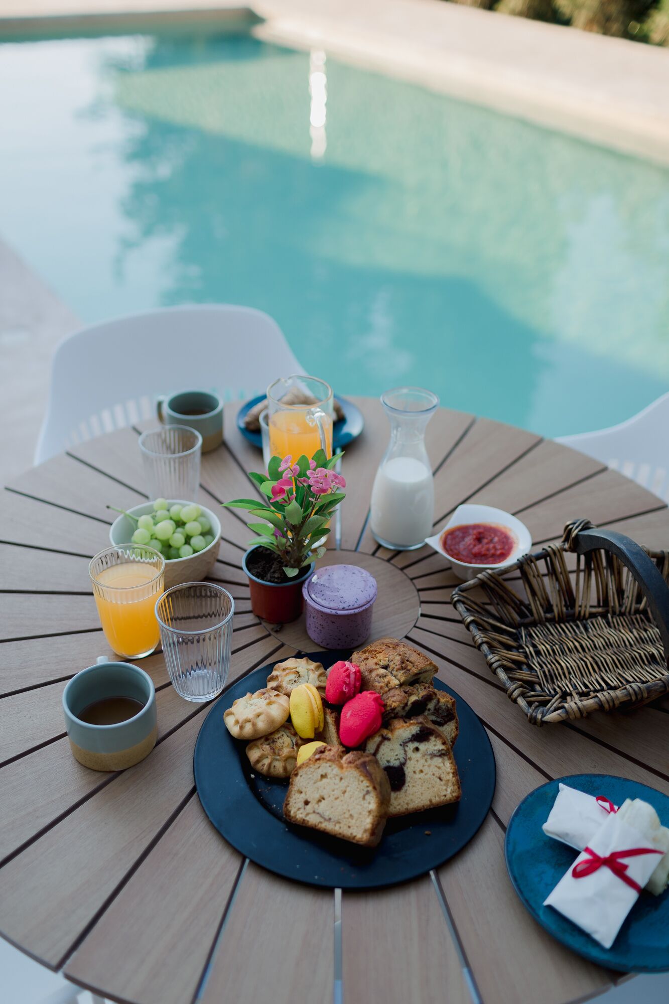 Un buffet de petit-déjeuner installé au bord de la piscine, avec une variété de plats, de boissons et une petite plante.