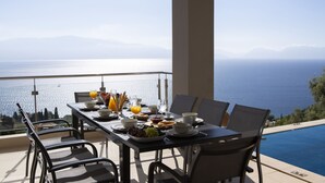 Tavolo apparecchiato per la colazione con vista sul mare e sulle montagne.