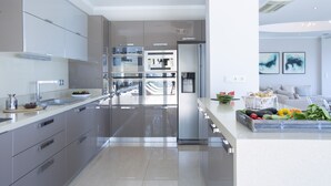 Una cucina moderna con elettrodomestici in acciaio inossidabile, un'isola ampia con frutta e verdura fresca e vista sull'area living.
