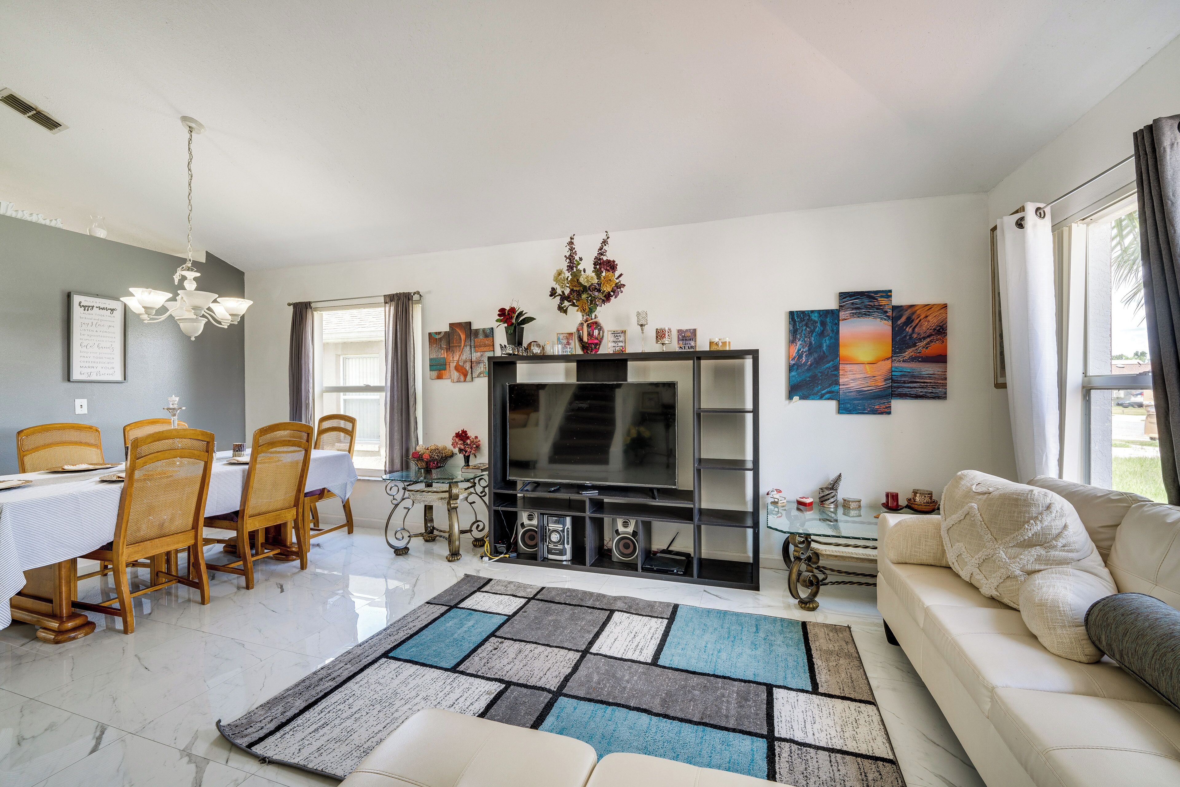 A dining area with a table and chairs, a TV stand with speakers, and a sofa in a living room.