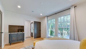 A bedroom with a bed, a dresser, and a window with curtains.