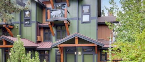 Un edificio de varios pisos con un diseño arquitectónico moderno, que combina elementos de madera y metal, ventanas amplias y un exterior bien cuidado.